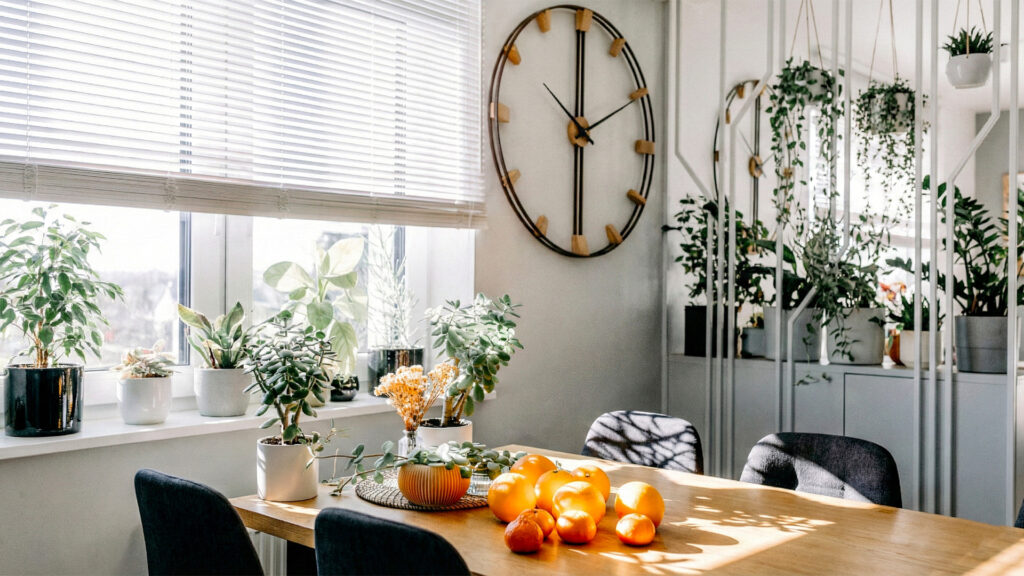 Duży zegar ścienny w stylu loft zawieszony w jadalni nad drewnianym stołem z owocami