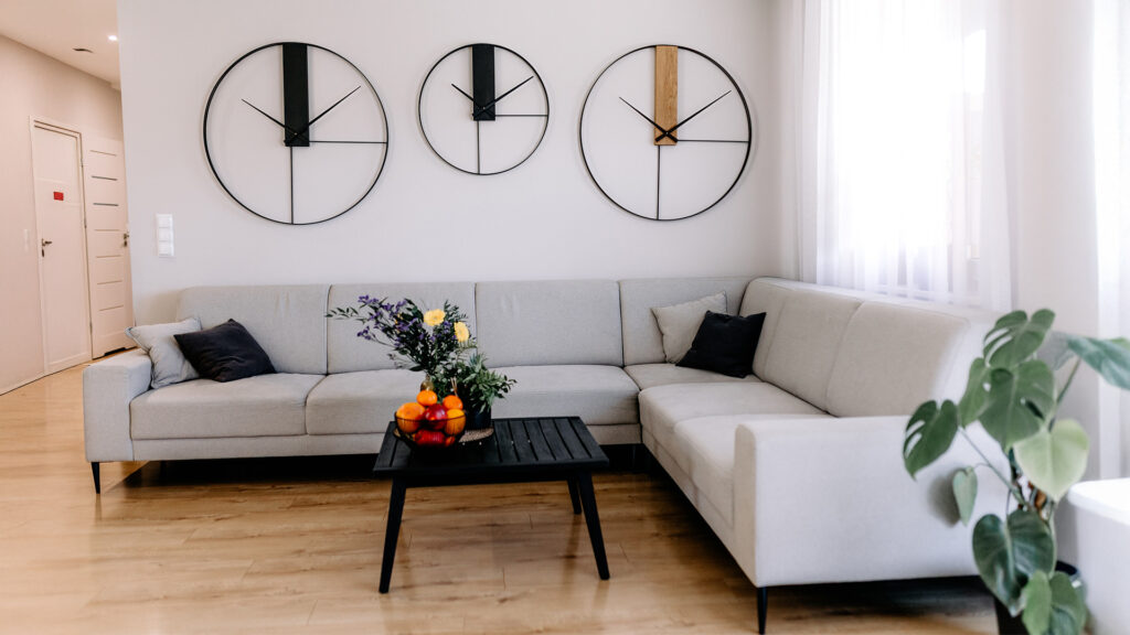 Trzy loftowe zegary ścienne o różnych wzorach zawieszone nad narożnikiem w nowoczesnym