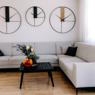 Trzy loftowe zegary ścienne o różnych wzorach zawieszone nad narożnikiem w nowoczesnym