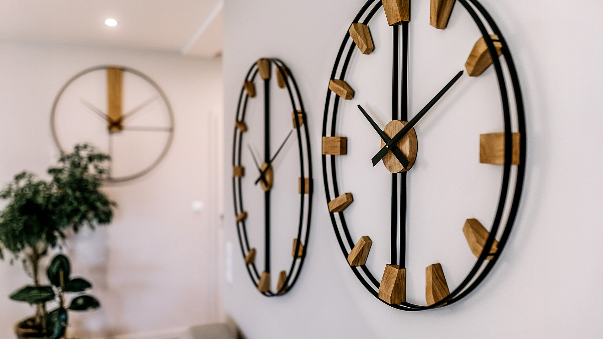 Dwa nowoczesne zegary ścienne z jasnego dębu na szarej ścianie w minimalistycznym