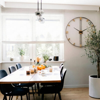 Prosty zegar ścienny z drewnianym środkiem i metalową obręczą w otoczeniu pnących roślin