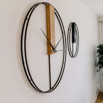 Nietypowy zegar ścienny z pionową deską dębową na białej ścianie, widok z boku